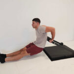 A person performing triceps dips with an Isophit Trainer